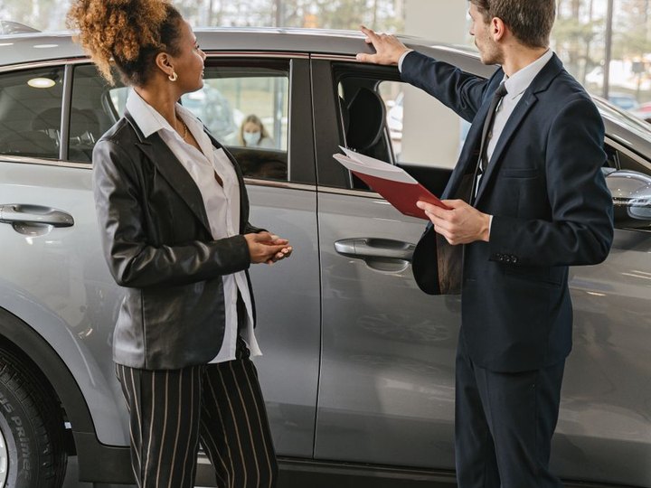 Salesperson showing a vehicle to a customer at a dealership