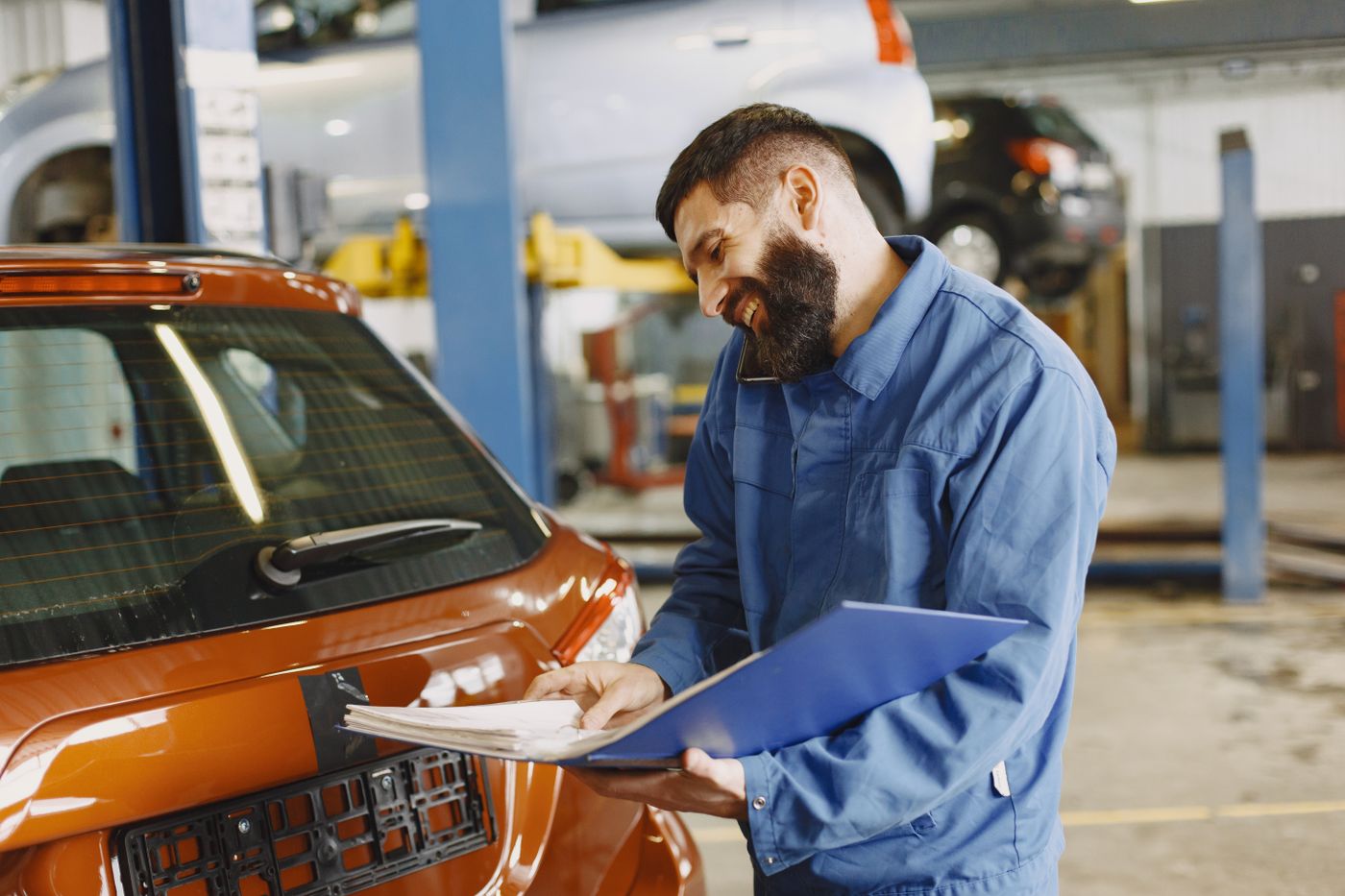 An inspector assessing a vehicle in a collision-repair workshop